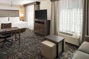 a hotel room with a bed and a desk with a computer at Homewood Suites By Hilton Ronkonkoma in Ronkonkoma