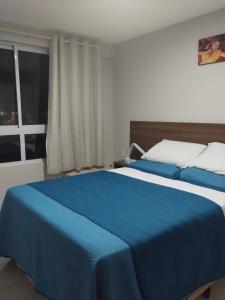 Un dormitorio con una cama azul y blanca y una ventana en Flat Jardins do Atlântico, frente mar, en João Pessoa