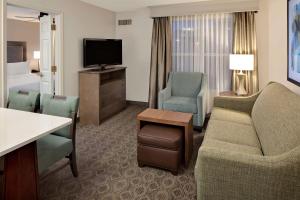 a hotel room with a couch and chairs and a television at Homewood Suites by Hilton Minneapolis-Mall Of America in Bloomington