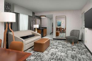 a living room with a couch and a table and a mirror at Embassy Suites by Hilton Dulles North Loudoun in Ashburn