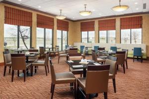 um restaurante com mesas, cadeiras e janelas em Hilton Garden Inn St. Louis Shiloh/O'Fallon IL em O'Fallon