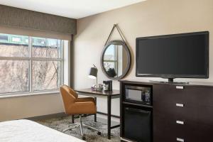 a bedroom with a television and a desk with a chair at Hampton Inn Portland Downtown Waterfront in Portland