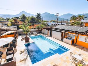 a swimming pool on the roof of a house with mountains in the background at VELINN Pousada Face Norte in Ilhabela