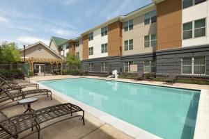 einen Pool mit Stühlen und ein Gebäude in der Unterkunft Homewood Suites by Hilton Dulles-North Loudoun in Ashburn