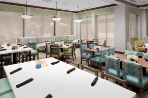 uma sala de jantar com mesas, cadeiras e janelas em Hilton Garden Inn Atlanta West/Lithia Springs em Lithia Springs