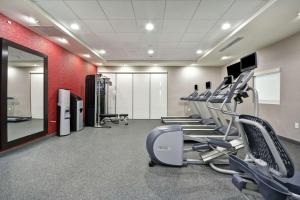 een fitnessruimte met loopbanden en crosstrainers en een rode muur bij Home2 Suites By Hilton Atlanta Lithia Springs in Lithia Springs