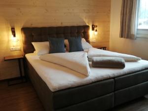 a large bed with white sheets and blue pillows at Apart Manuel in Mayrhofen
