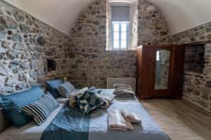 a bedroom with a bed and a stone wall at ENGLEZENA'S GUESTHOUSE in Leonidion