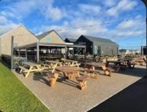 a group of picnic tables in front of a building at Three Jays in Saint Osyth