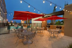 Home2 Suites by Hilton Clarksville/Ft. Campbell في كلاركسفيل: فناء به طاولات وكراسي به مظلات حمراء