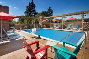 Home2 Suites By Hilton Murfreesboro في مورفريسبورو: حمام سباحة مع كراسي ملونة وطاولة وكراسي
