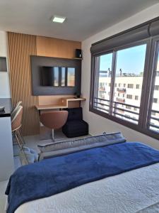 een slaapkamer met een groot bed, een bureau en een tv bij Lindo Studio NOVO no JP Redenção - Rofftop com vista espetacular in Porto Alegre