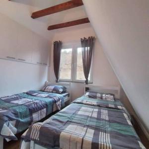 two beds in a room with a window at Villa Piano - Cheerful 3-bedroom villa with BBQ grill in Novoberdo