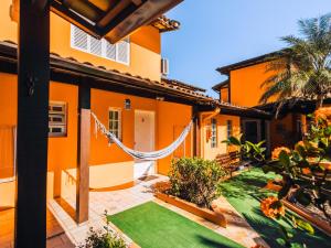Una casa naranja con una hamaca en el patio en VELINN Pousada Face Norte, en Ilhabela