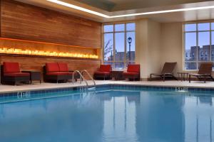a pool in a hotel room with red chairs and a pool at Embassy Suites by Hilton Jackson North Ridgeland in Ridgeland