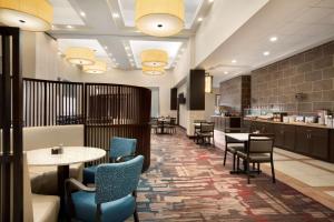 a restaurant with tables and chairs and a bar at Embassy Suites by Hilton Jackson North Ridgeland in Ridgeland