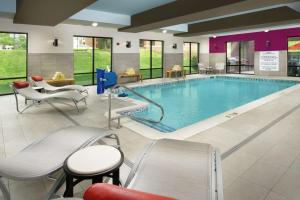 a pool in a hotel room with chairs and a table at Home2 Suites by Hilton Louisville East Hurstbourne in Louisville