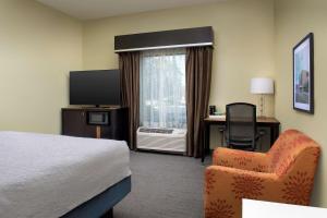 a hotel room with a bed and a chair and a television at Hampton Inn Knoxville Clinton I-75 in Clinton