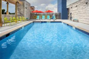 a swimming pool with blue water and yellow chairs and tables at Home2 Suites By Hilton Columbia Southeast Fort Jackson in Columbia
