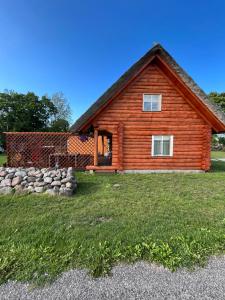 a log cabin with a stone wall in front of it at Jürivärava Saunamaja in Kantsi