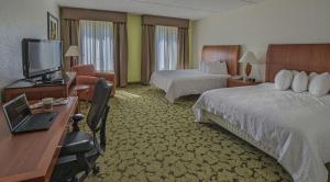 a hotel room with two beds and a desk with a laptop at Hilton Garden Inn Auburn/Opelika in Auburn