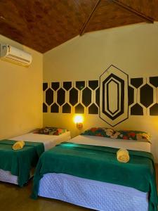 a bedroom with two beds with green and white sheets at Bangalôs do Tapajós in Alter do Chao