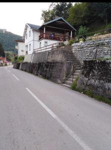 une maison sur le côté d'un mur à côté d'une route dans l'établissement Apartman Mely, à Kulen Vakuf