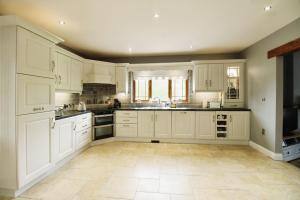 uma grande cozinha com armários brancos e piso em azulejo em Tirmacspird Road 