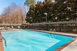 una piscina azul con una valla y árboles en Hampton Inn & Suites Atlanta Airport West Camp Creek Pkwy en Atlanta