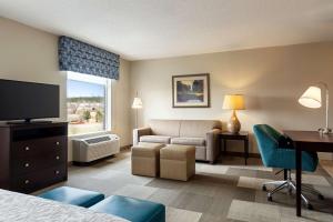 a hotel room with a bed and a couch and a desk at Hampton Inn & Suites Atlanta Airport West Camp Creek Pkwy in Atlanta