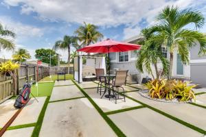 eine Terrasse mit einem Tisch, einem Sonnenschirm und Palmen in der Unterkunft Lush West Park Escape with Pool Access! in Miami Gardens