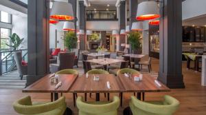 un restaurante con mesas de madera y sillas verdes en Hilton Garden Inn Charleston Waterfront/Downtown en Charleston