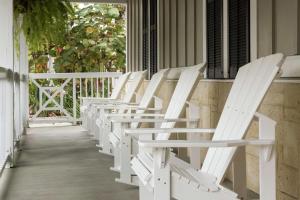 Hampton Inn New Smyrna Beach في نيو سميرنا بيتش: صف من الكراسي البيضاء جالسة على الشرفة