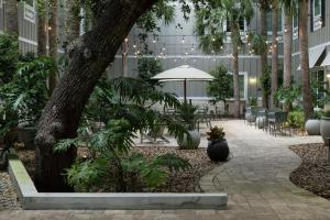 un patio con un árbol, mesas y sillas en Hampton Inn New Smyrna Beach en New Smyrna Beach