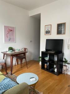 een woonkamer met een tafel en een flatscreen-tv bij Cosy Shoreditch flat in Londen