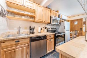 a kitchen with wooden cabinets and a stainless steel refrigerator at Meticulously Updated Unit With Lots of Thoughtful Upgrades Ski In, Walk to Town PM1B in Breckenridge