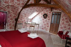 a room with a red bed with a table and a chair at La Halte du Clos in Cour-Cheverny