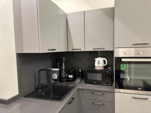 a kitchen with white cabinets and a sink and a microwave at Maison d'Or - Via Cecchi in Genoa