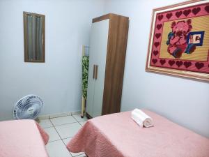 Habitación con cama rosa y ventilador. en Apto Recanto Aconchego (B-E 32), en Rio Verde