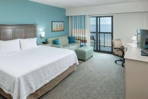 a hotel room with a bed and a balcony at Hampton Inn & Suites by Hilton Carolina Beach Oceanfront in Carolina Beach