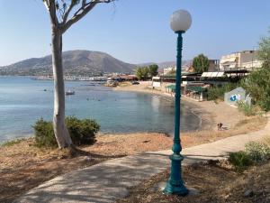 Athens Riviera-SEAVIEW Apartment-Walk to the beach-Minutes away from Sounio-Updated 2023! في Áyios Yeóryios: ضوء الشارع على الرصيف بجانب الشاطئ