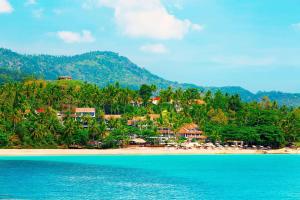 a resort on a beach with trees and blue water at Sheraton Samui Resort in Chaweng Noi Beach