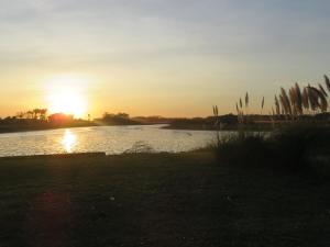 einen Sonnenuntergang über einem Wasserkörper mit Sonnenuntergang in der Unterkunft COMPLEJO LA ISLA MAR CHIQUITA in Balneario Mar Chiquita