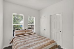 a white bedroom with a bed and two windows at The Village Downtown West in Indianapolis