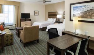 a hotel room with two beds and a table and chairs at Homewood Suites by Hilton Cape Canaveral-Cocoa Beach in Cape Canaveral