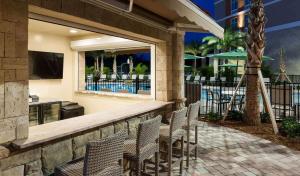a patio with chairs and a bar with a view of a pool at Homewood Suites by Hilton Cape Canaveral-Cocoa Beach in Cape Canaveral