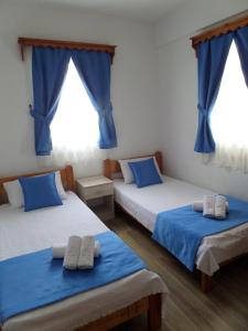 two beds in a room with blue curtains at Apart Turgutreis in Turgutreis