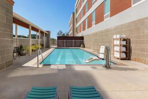 a swimming pool with blue chairs next to a building at Home2 Suites By Hilton Statesboro in Statesboro