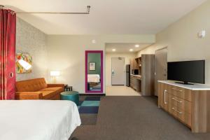 a hotel room with a bed and a flat screen tv at Home2 Suites By Hilton Statesboro in Statesboro