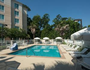 uma piscina num hotel com cadeiras e um escorrega em Hilton Garden Inn Tallahassee Central em Tallahassee